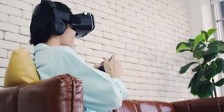 一个戴着虚拟现实眼镜的男人在现代家庭体验创新技术，一个帅气的男人在阳光明媚的日子用VR眼镜玩游戏。
