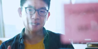 特写英俊的亚洲年轻人在使用笔记本电脑聊天，使用网络摄像头，户外技术工作互联网。他正在家里开视频会议