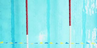 女子游泳运动员做蛙泳在一个清澈的蓝色游泳池通过在一个泳道的摄像机下面