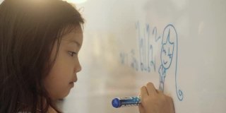 亚洲女孩在白板上画画，家庭教育的概念。
