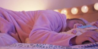 一位母亲带着一个小孩在她的卧室里学习的时候睡着了，她在照顾她刚出生的孩子。COVID-19大流行期间的在家教育。