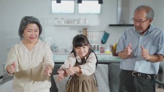 亚洲家庭小女孩和祖父母一起在客厅跳舞。儿童和老人和妇女用笑脸感受乐趣。可爱的家庭和活动理念的快乐时刻视频素材模板下载