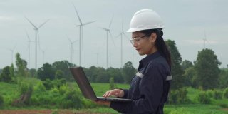 在泰国风电场，检查工程师正在用笔记本电脑准备和检查风力涡轮机的进度。