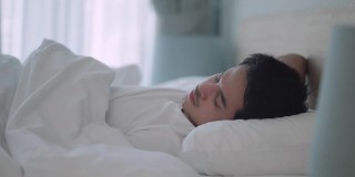 亚洲男人睡甜蜜的梦在一个舒适的午睡在床上在房子里的卧室