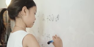 快乐的亚洲女孩教数学科目为她的妹妹在白板上在家上学，呆在家里的概念。
