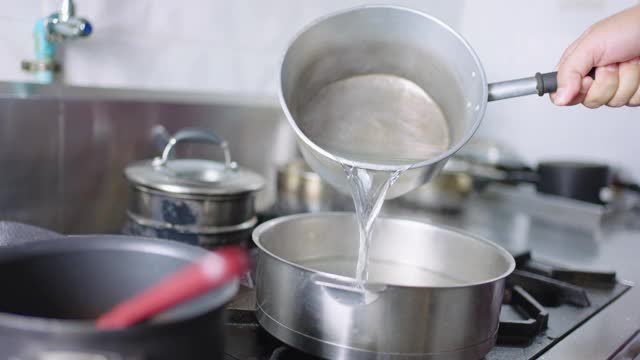 SLO MO:厨师用手将热水倒入锅中。