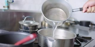 SLO MO:厨师用手将热水倒入锅中。