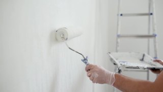 英俊成熟的男人在公寓里修理。那个人用滚筒把墙刷成白色。做你自己。DIY。视频素材模板下载