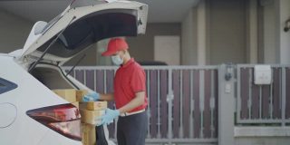 4 k慢动作视频。一名身穿红色制服的男性快递员寄包裹盒子在寄给收件人之前喷洒清洁酒精新标准的概念。