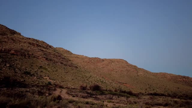 满月随着星星和移动的卫星在荒野山上升起的时间流逝