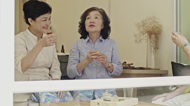 轻松的中国资深女性在咖啡馆敬酒