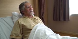 亚洲老病人坐在床上向医院的医生解释他的病情