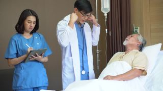 医生用听诊器检查老年患者，用平板电脑检查心肺，护士在医院病床上与老年患者交谈视频素材模板下载