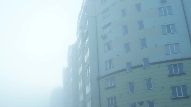 多层住宅楼在浓重的晨雾中，背景