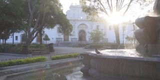 危地马拉安提瓜中央公园美人鱼喷泉的日出——鸽子在危地马拉安提瓜美丽的殖民公园喷泉上空飞翔