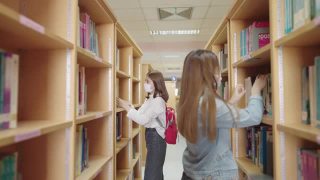 女学生们在大学图书馆的书架上寻找书籍。视频素材模板下载