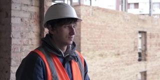 一个戴着白色防护帽的建筑工人正在用对讲机进行谈判。建筑测量和建筑重建。