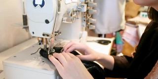 一个女裁缝在打字机上缝纫的特写。服装设计师。在工厂工作的过程中。一位女裁缝在车间里做时髦的衣服。的职业。时尚风格。