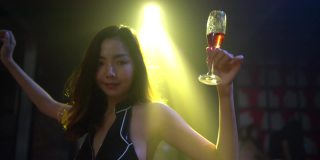 亚洲女人拿着香槟杯在夜店跳舞
