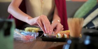 在家吃带酱料的塑料包装寿司卷的妇女