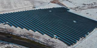 在雪地里使用太阳能可再生电池板生产的太阳能农场在冬天没有汽车或卡车的空旷道路附近供电