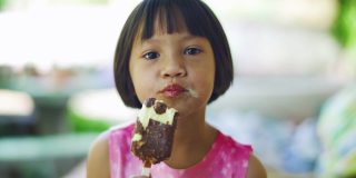 可爱的女孩正带着积极的情绪，放松，享受吃巧克力冰淇淋零食。