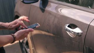 一位女士用手机和移动应用程序打开一辆轻型汽车的车门。汽车租赁。视频素材模板下载