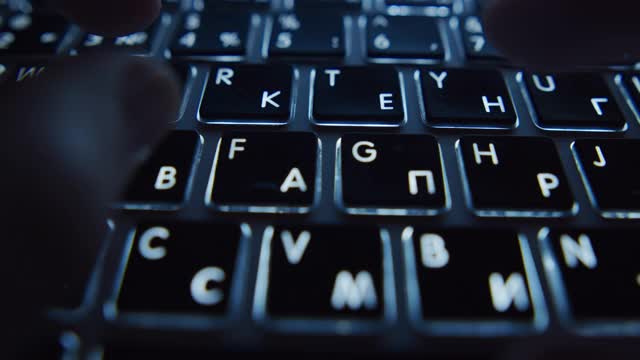 女性的手在晚上敲击笔记本电脑的键盘