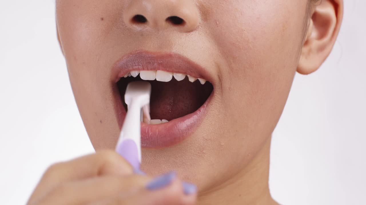 健康的习惯。近距离的年轻女子刷牙她完美的白牙齿，慢动作