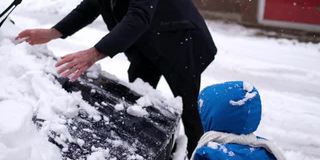 一家人在冬天清除汽车上的雪