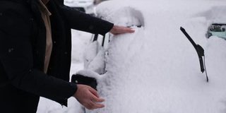 一家人在冬天清除汽车上的雪