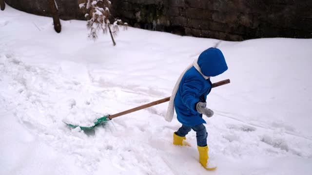 小男孩在冬天铲雪。