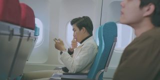 男子在飞机上浏览智能手机
