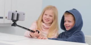 孩子博主与粉丝聊天，看着家里的智能手机屏幕直播。小男孩和小女孩在自拍
