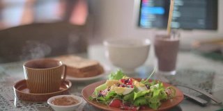 早餐健康食品沙拉，水果奶昔，烤面包在餐桌上与数字平板电脑