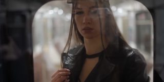 时尚模特在地铁车厢里透过玻璃拍照。漂亮的女孩看着地铁车厢玻璃的反光。FHD视频。基辅地铁