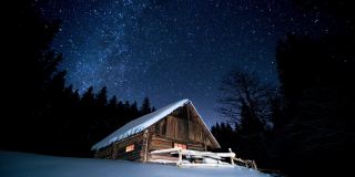 美丽的木屋在冬天的森林里闪烁的星星下。Cinemagraph。