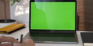 女孩看绿色屏幕的笔记本电脑在客厅看视频