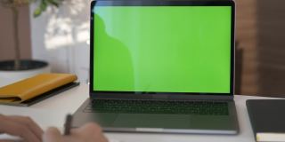 女孩看绿色屏幕的笔记本电脑在客厅看视频