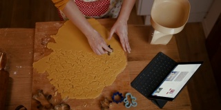 一个女人正在切面团做星星形状的圣诞饼干