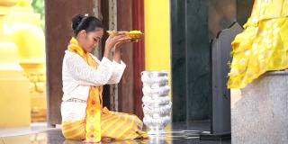 缅甸妇女在一座寺庙里表达她们的敬意。穿着缅甸传统服装的东南亚年轻女孩参观佛教寺庙。