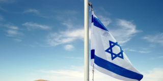 以色列国旗在沙漠的屋顶上迎风缓慢移动
