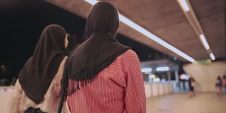 两个年轻的亚洲穆斯林朋友高兴地向镜头展示购物袋，现代穆斯林生活方式，资本主义消费消费，折扣销售产品，享受购物中心，城市生活