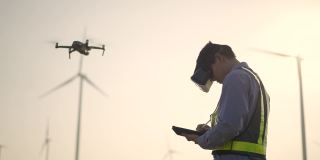 年轻男性工程师在亚子集的风力发电站工作，用VR眼镜操控无人机飞行