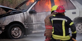 后视图亚洲消防队员操作消防软管在一辆汽车