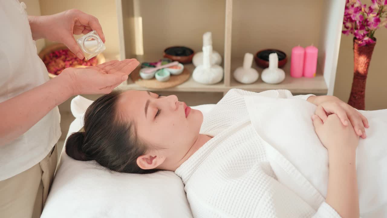 年轻的亚洲女性正在接受面部按摩，精油用于护肤