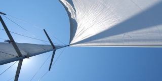 在公海上航行的帆船。风吹着游艇的白帆，阳光灿烂。概念:航海假期，自由