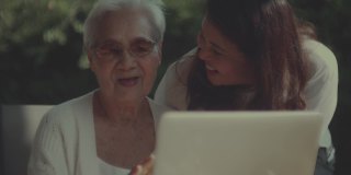 亚洲妇女和她的母亲一起使用笔记本电脑在家里
