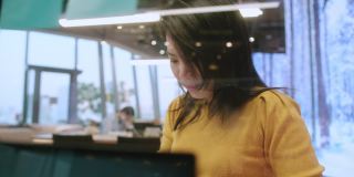 具有吸引力的自由职业亚洲女性创意人士，穿着休闲的黄色布手点和书写纸笔记贴提醒在共同工作空间的新生活方式与思考和新鲜的情感