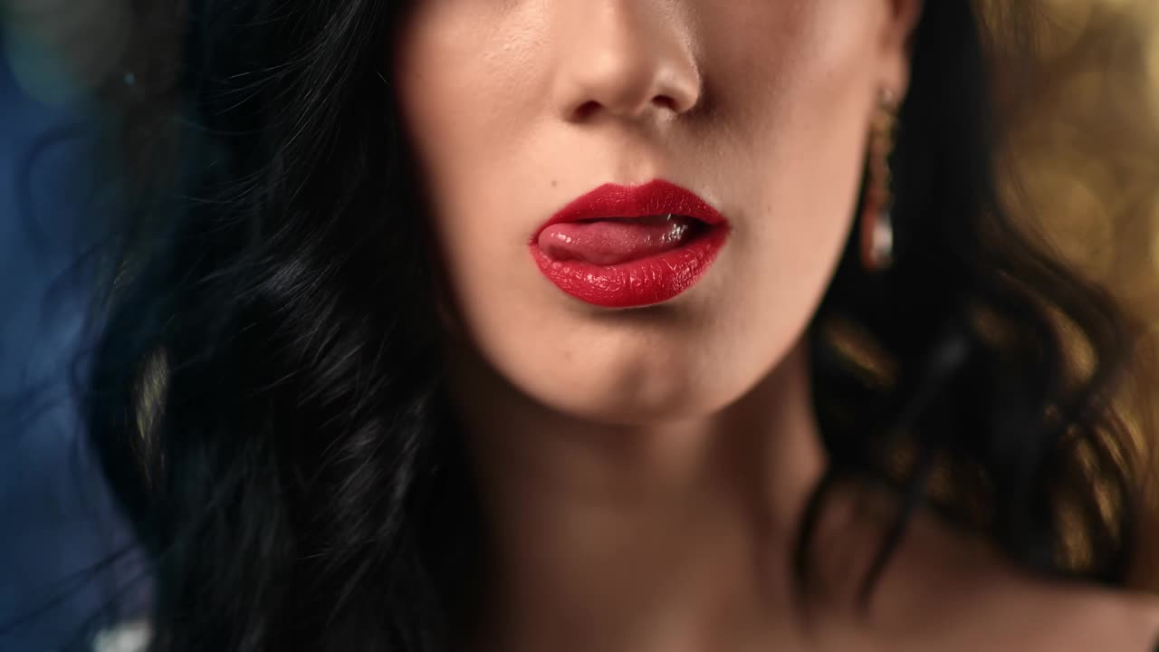 特写性感的黑发女人舔舌头，咬红色的嘴唇摆迪斯科散拍。4k Dragon RED摄像机